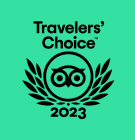Green badge with a stylized owl in the center, surrounded by laurel leaves. Text above and below reads Travelers Choice 2023.